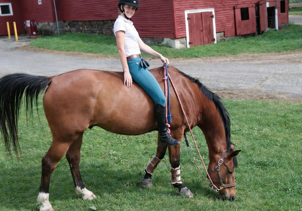 Girl grazing bay horse while riding bareback in CT